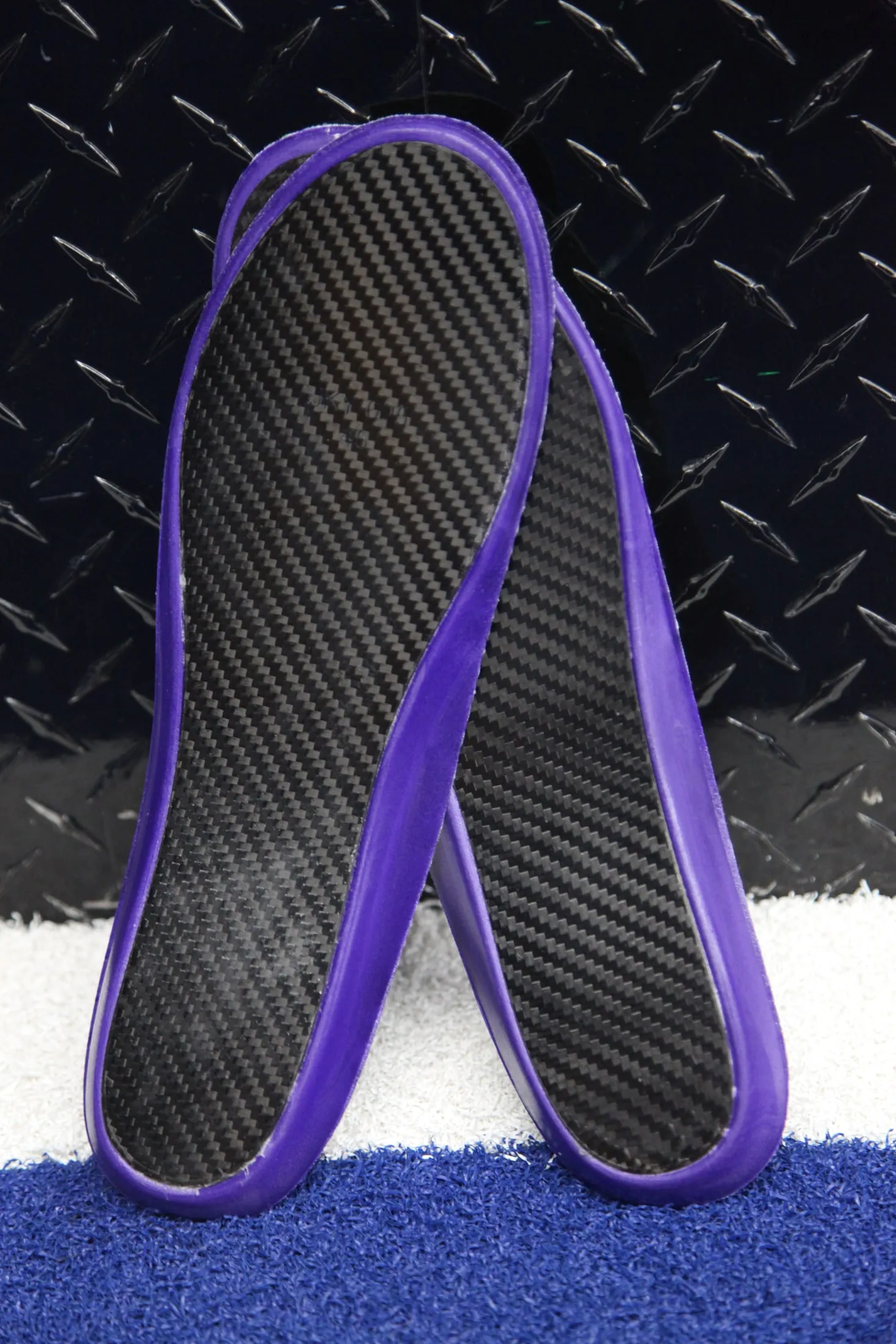 Underside of a CRBN V2 pair: carbon fibre weave and purple rim, resting on a gym bench