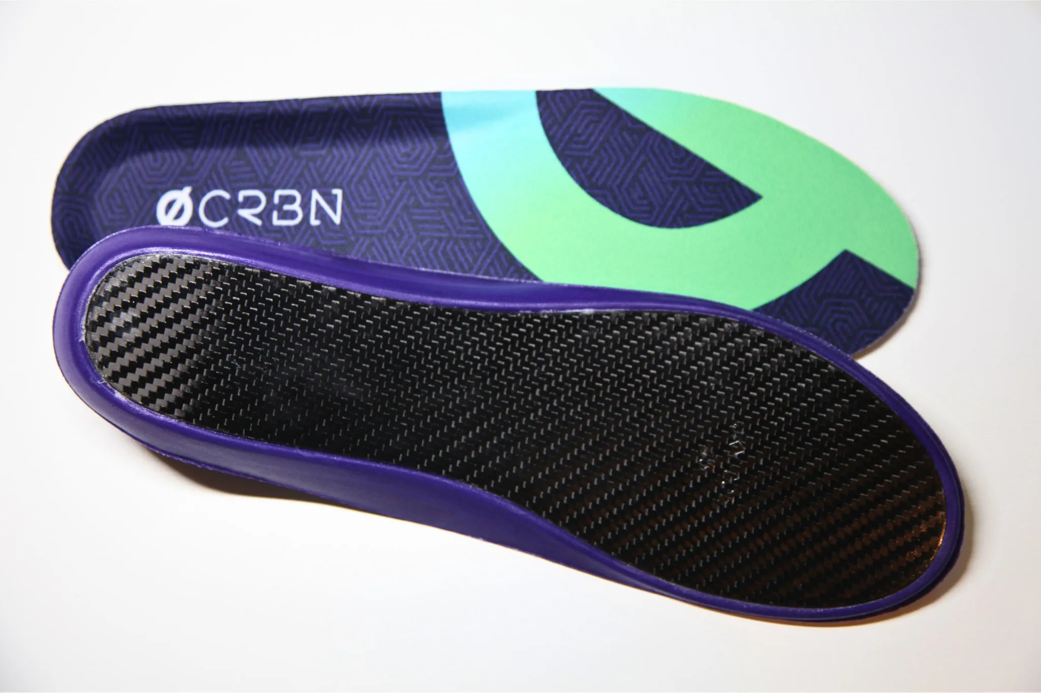 CRBN V2 insole pair: printed top sheet above, and the carbon fibre baseplate framed by its purple support rim below